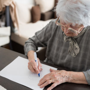 Senior woman writing at a desk.
